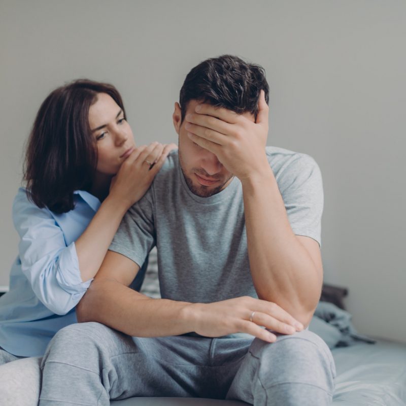 Female consoles her sad boyfriend who has depression and some problems, pose at bedroom on bed